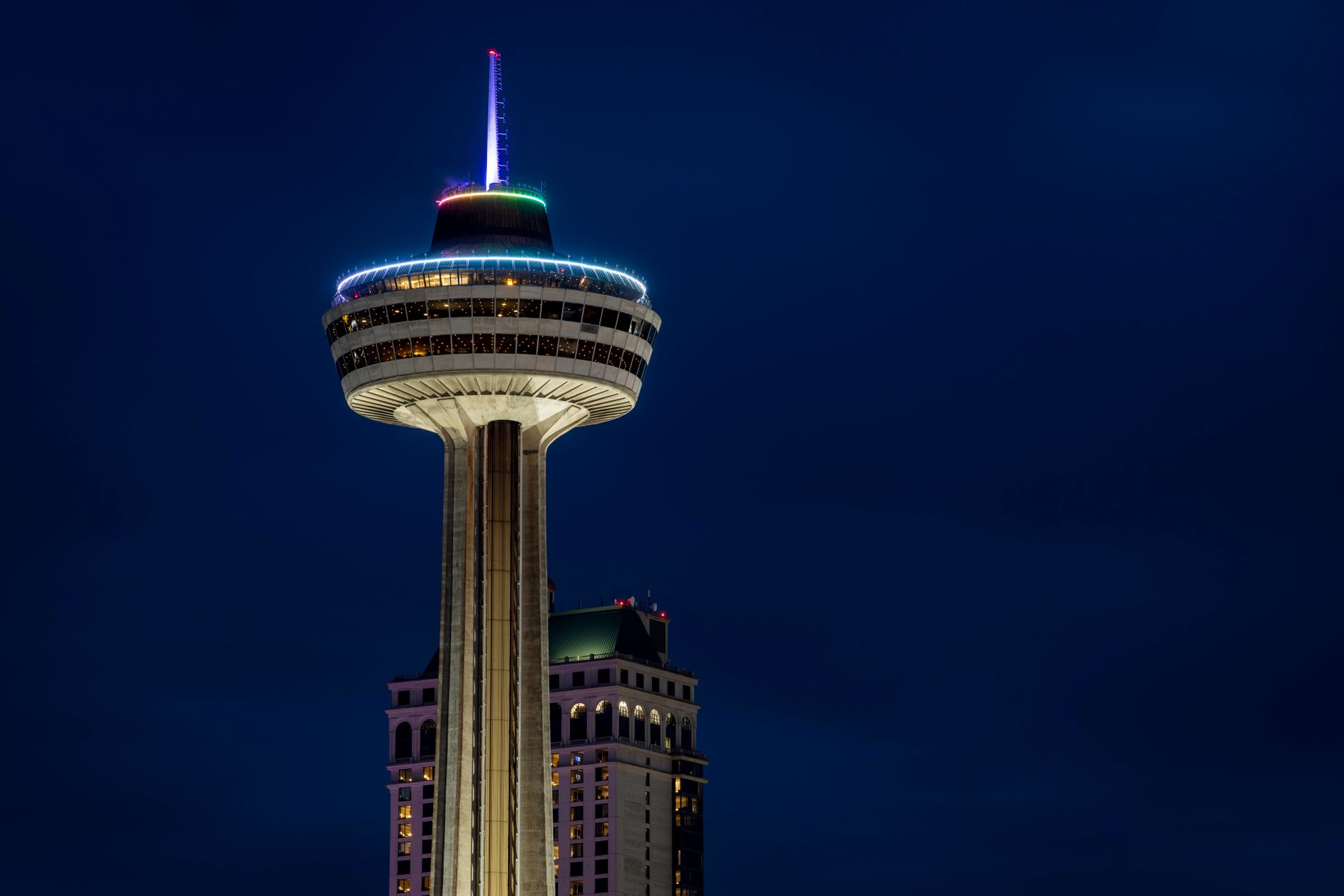 View of Skylon Tower in Niagara Falls beautifully lit against a dark night sky.